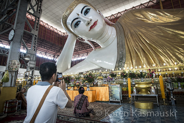 Tourist photographs the famous Reclining Buddha in Yangon, Myanmar.